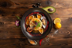 Baked squid rings with rice and spices in the black plate stock photos Baked squid rings with rice and spices in the black plate stock photos
