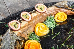 Baked sturgeon fish with rosemary, lemon and passion fruit on plate on wooden background close up. stock image Baked sturgeon fish with rosemary, lemon and passion fruit on plate on wooden background close up. stock image