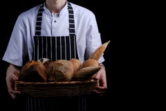 Baker holds basket of bread on black background isolated stock images Baker holds basket of bread on black background isolated stock images