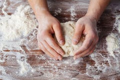 Baker προετοιμάζει τη ζύμη σε έναν ξύλινο πίνακα, τα αρσενικά χέρια ζυμώνουν τη ζύμη με το αλεύρι στοκ φωτογραφία με δικαίωμα ελεύθερης χρήσης Baker προετοιμάζει τη ζύμη σε έναν ξύλινο πίνακα, τα αρσενικά χέρια ζυμώνουν τη ζύμη με το αλεύρι στοκ φωτογραφία με δικαίωμα ελεύθερης χρήσης