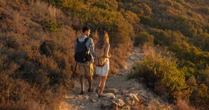 Bakre sikt av man- och kvinnafotvandrare som trekking en stenig bana på kullesidan Undersökande natur för fotvandrarepar som går royaltyfri foto Bakre sikt av man- och kvinnafotvandrare som trekking en stenig bana på kullesidan Undersökande natur för fotvandrarepar som går royaltyfri foto