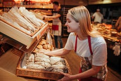 Bakset Griff der jungen Frau mit frischem Brot im Gemischtwarenladen Sie setzte es auf Regal und Lächeln Geschmackvoll und delisi stockfotos Bakset Griff der jungen Frau mit frischem Brot im Gemischtwarenladen Sie setzte es auf Regal und Lächeln Geschmackvoll und delisi stockfotos