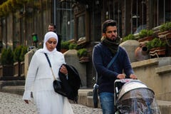Young Azerbaijani couple in litter. A woman in a white hijab and a man carrying a stroller with a baby royalty free stock image Young Azerbaijani couple in litter. A woman in a white hijab and a man carrying a stroller with a baby royalty free stock image