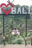 BALI INDONESIEN - JANUARI 23, 2018: Ung kvinna på gungan i djungeln Tropisk paradisgunga _ arkivfoto BALI INDONESIEN - JANUARI 23, 2018: Ung kvinna på gungan i djungeln Tropisk paradisgunga _ arkivfoto