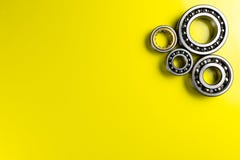 Ball bearing lying on a yellow background with copy space on the left side. Flat view from above. stock images Ball bearing lying on a yellow background with copy space on the left side. Flat view from above. stock images