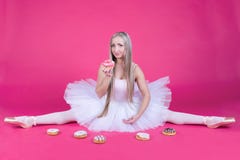 Ballerine faisant une fente dans la jupe de tutu mangeant un beignet image libre de droits Ballerine faisant une fente dans la jupe de tutu mangeant un beignet image libre de droits
