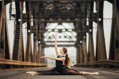 Ballerine s'asseyant dans la pose de ficelle sur la route et les rails à côté des appuis en métal image libre de droits Ballerine s'asseyant dans la pose de ficelle sur la route et les rails à côté des appuis en métal image libre de droits