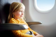 Bambina adorabile che viaggia in aeroplano Bambino che si siede dalla finestra degli aerei e che guarda fuori Fotografia Stock Libera da Diritti Bambina adorabile che viaggia in aeroplano Bambino che si siede dalla finestra degli aerei e che guarda fuori Fotografia Stock Libera da Diritti