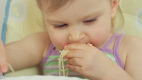 Bambina affascinante che mangia gli spaghetti con le sue dita e che lo gode video d archivio Bambina affascinante che mangia gli spaghetti con le sue dita e che lo gode video d archivio