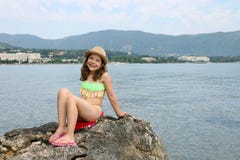 Bambina che si siede su una roccia entro le vacanze estive del mare fotografie stock libere da diritti Bambina che si siede su una roccia entro le vacanze estive del mare fotografie stock libere da diritti