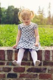Bambina che si siede sulla parete, felice di essere scalzo immagine stock Bambina che si siede sulla parete, felice di essere scalzo immagine stock