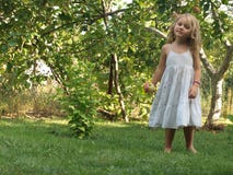 Bambina con una mela in sua mano in mezzo al giardino immagine stock Bambina con una mela in sua mano in mezzo al giardino immagine stock