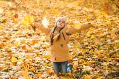 Bambina felice che getta le foglie cadute su, giocando nel parco di autunno fotografia stock libera da diritti Bambina felice che getta le foglie cadute su, giocando nel parco di autunno fotografia stock libera da diritti
