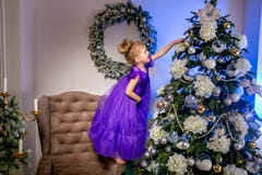 Bambina graziosa 4 anni in un vestito blu Bambino nella stanza di Natale con l'orologio teddybear e grande, albero di Natale, pol fotografia stock libera da diritti Bambina graziosa 4 anni in un vestito blu Bambino nella stanza di Natale con l'orologio teddybear e grande, albero di Natale, pol fotografia stock libera da diritti