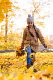 Bambina positiva che cammina tramite le foglie cadute nel parco di autunno il giorno allegro dell'autunno, verticale immagine stock Bambina positiva che cammina tramite le foglie cadute nel parco di autunno il giorno allegro dell'autunno, verticale immagine stock