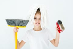 Bambina sorridente che tiene i vari rifornimenti di pulizia su bianco fotografia stock Bambina sorridente che tiene i vari rifornimenti di pulizia su bianco fotografia stock