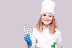 Bambina sorridente nelle pillole uniformi mediche della tenuta per salute Medico raccomanda le pillole della medicina fotografie stock libere da diritti Bambina sorridente nelle pillole uniformi mediche della tenuta per salute Medico raccomanda le pillole della medicina fotografie stock libere da diritti