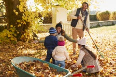 Bambini che aiutano i genitori a raccogliere Autumn Leaves In Garden Immagini Stock Libere da Diritti Bambini che aiutano i genitori a raccogliere Autumn Leaves In Garden Immagini Stock Libere da Diritti