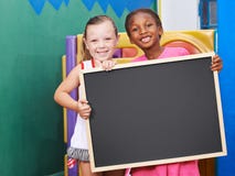 Bambini che tengono lavagna vuota in scuola materna fotografie stock Bambini che tengono lavagna vuota in scuola materna fotografie stock
