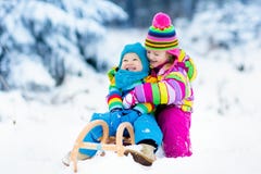 Bambini sul giro della slitta Precipitandosi attraverso la neve Divertimento della neve di inverno fotografia stock Bambini sul giro della slitta Precipitandosi attraverso la neve Divertimento della neve di inverno fotografia stock