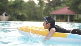 Bambino asiatico felice che gioca nella piscina con il fronte di sorriso Bambino asiatico felice che gioca nella piscina con il fronte di sorriso