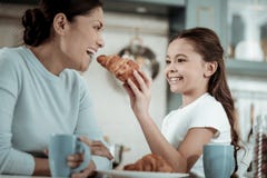 Bambino che alimenta sua madre con un croissant immagini stock Bambino che alimenta sua madre con un croissant immagini stock