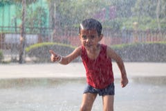 Bambino che gioca nella pioggia che cade nel parco dell'acqua fotografia stock Bambino che gioca nella pioggia che cade nel parco dell'acqua fotografia stock