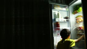 Bambino che mangia davanti al frigorifero nel mezzo della notte Bambino che mangia davanti al frigorifero nel mezzo della notte