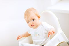 Bambino che si siede nella presidenza del bambino e che fa fronte divertente fotografie stock Bambino che si siede nella presidenza del bambino e che fa fronte divertente fotografie stock