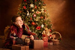 Bambino che sogna sotto l'albero di natale, bambino di Natale del ragazzo del buon anno immagini stock libere da diritti Bambino che sogna sotto l'albero di natale, bambino di Natale del ragazzo del buon anno immagini stock libere da diritti