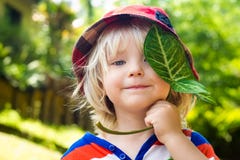 Bambino felice sveglio che tiene una foglia immagine stock libera da diritti Bambino felice sveglio che tiene una foglia immagine stock libera da diritti
