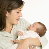 Bambino sorridente della holding della madre. immagini stock Bambino sorridente della holding della madre. immagini stock