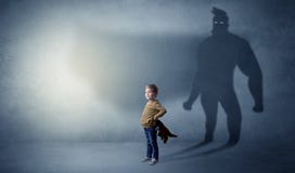 Bambino sveglio con l'ombra dell'eroe dietro fotografie stock Bambino sveglio con l'ombra dell'eroe dietro fotografie stock