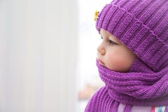 Bambino triste che esamina la finestra durante il giorno di inverno freddo in vestiti caldi Fotografia Stock Bambino triste che esamina la finestra durante il giorno di inverno freddo in vestiti caldi Fotografia Stock