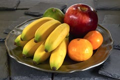 Banaan, appel en mandarin op een metaalplaat, op een zwarte leisteen royalty-vrije stock afbeelding Banaan, appel en mandarin op een metaalplaat, op een zwarte leisteen royalty-vrije stock afbeelding
