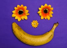 Banana and flowers make happy smile on violet bacgrounf top view flat lay abstract collage stock images Banana and flowers make happy smile on violet bacgrounf top view flat lay abstract collage stock images