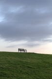 Banc abandonné devant un ciel foncé sur un barrage à la Mer du Nord photographie stock Banc abandonné devant un ciel foncé sur un barrage à la Mer du Nord photographie stock