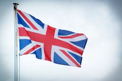A bandeira de Union Jack do Reino Unido funde no vento imagem de stock A bandeira de Union Jack do Reino Unido funde no vento imagem de stock