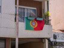Bandeira portuguesa que haning de um balcão região em Vila do Conde, Porto, Portugal imagem de stock royalty free Bandeira portuguesa que haning de um balcão região em Vila do Conde, Porto, Portugal imagem de stock royalty free