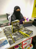 Small business kiosks are stall selling books for fundraising. Woman in hijab and veil at the shop
