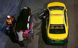 BANGKOK, THAILAND - OCTOBER 20: Taxi and tuktuk drivers park next to each other while waiting for passengers while a policeman pu royalty free stock photography BANGKOK, THAILAND - OCTOBER 20: Taxi and tuktuk drivers park next to each other while waiting for passengers while a policeman pu royalty free stock photography