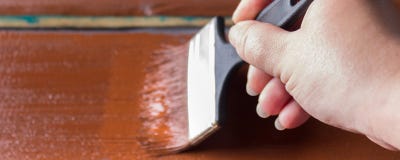 Banner. Brush With Paint In Hand. A Man Paints Blue Boards In A Brown Paint Brush. Stock Photos