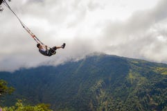 Banos, Ecuador: Boy swinging at a treehouse at the top of mountain. Tungurahua volcano behind