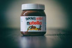 Barattolo di Nutella sopra una tavola di legno fotografie stock libere da diritti Barattolo di Nutella sopra una tavola di legno fotografie stock libere da diritti