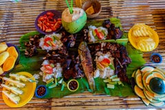 Barbecue of chicken, pork and fish is served on bamboo leaves with vegetables and fruits. Filipino cuisine