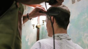 Barbeiro farpado novo que está e que faz o corte de cabelo à moda do homem atrativo com a tosquiadeira no barbeiro O homem farpad filme Barbeiro farpado novo que está e que faz o corte de cabelo à moda do homem atrativo com a tosquiadeira no barbeiro O homem farpad filme