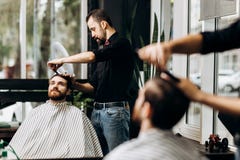 Barber dressed in a black shirt with a red bow tie scissors the man`s hair in a barbershop stock photography Barber dressed in a black shirt with a red bow tie scissors the man`s hair in a barbershop stock photography