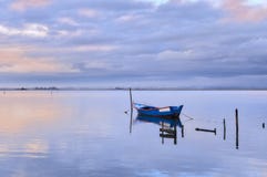Barca blu da solo sulla laguna al tramonto fotografia stock libera da diritti Barca blu da solo sulla laguna al tramonto fotografia stock libera da diritti