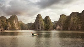 Barco que pasa delante de las colinas místicas en la bahía de Halong imagen de archivo libre de regalías Barco que pasa delante de las colinas místicas en la bahía de Halong imagen de archivo libre de regalías