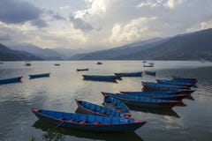Barcos de madeira azuis na água contra o contexto do lago e do vale da montanha povos em barcos de prazer na noite imagens de stock Barcos de madeira azuis na água contra o contexto do lago e do vale da montanha povos em barcos de prazer na noite imagens de stock